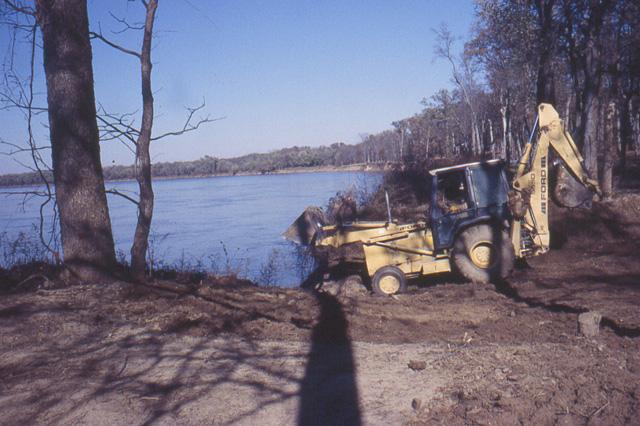 A backhoe filling in the excavated area