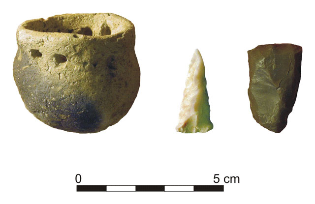 Examples of some of the exhibit quality artifacts recovered from excavations in the North Block, Fall 2000. Left: miniature pottery jar, with opposed pairs of holes at the neck, for suspension. Center: complete trianular arrow point, Madison type; this point appears to be undamaged; perhaps it was lost rather than discarded. Right: complete endscraper of Wyandotte chert, scraping end at the top, haft end inserted into handle at the bottom; endscrapers are primarily hide-working tools; the sides and end have been resharpened, and this reworking has made the left side narrower than the hafted portion of the tool.