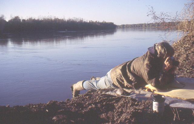 A person lying on river bank taking photo