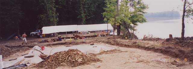 Two canopy tents over dig site and people working at the site
