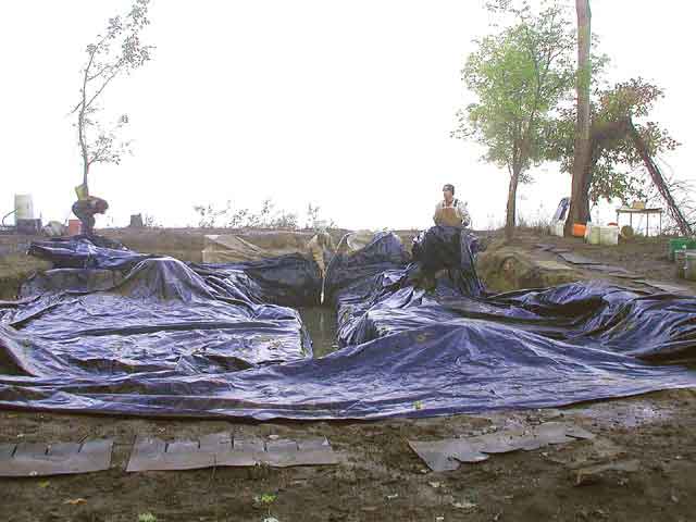 Two people working excavation site covered with tarps