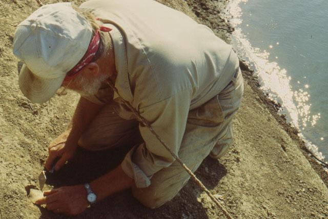Patrick Munson collecting an artifact from the river bank