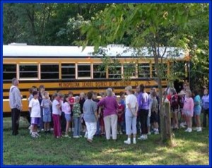 Fourth grade students and adults standing in front of school bus