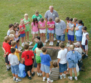Fourth grade students and adults encircling a rectangular excavation example
