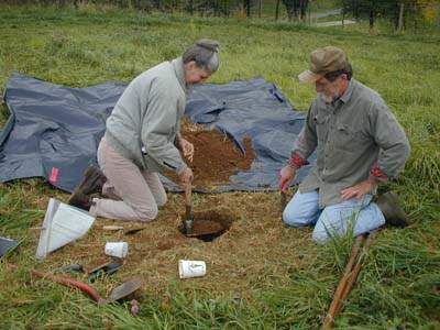 Sundae Murphy and Richard Lyons use a trenching tool to lift out loosened soil, and stockpile it on plastic for screening