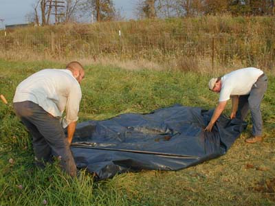 Stockpiled soil from auguring is wrapped up burrito-style in plastic, and then rolled over the auger hole, to prevent the excavated soil from drying out and getting rained on and to preserve the soil profile.