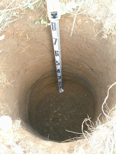 Auger hole with measuring tape to measure the depth